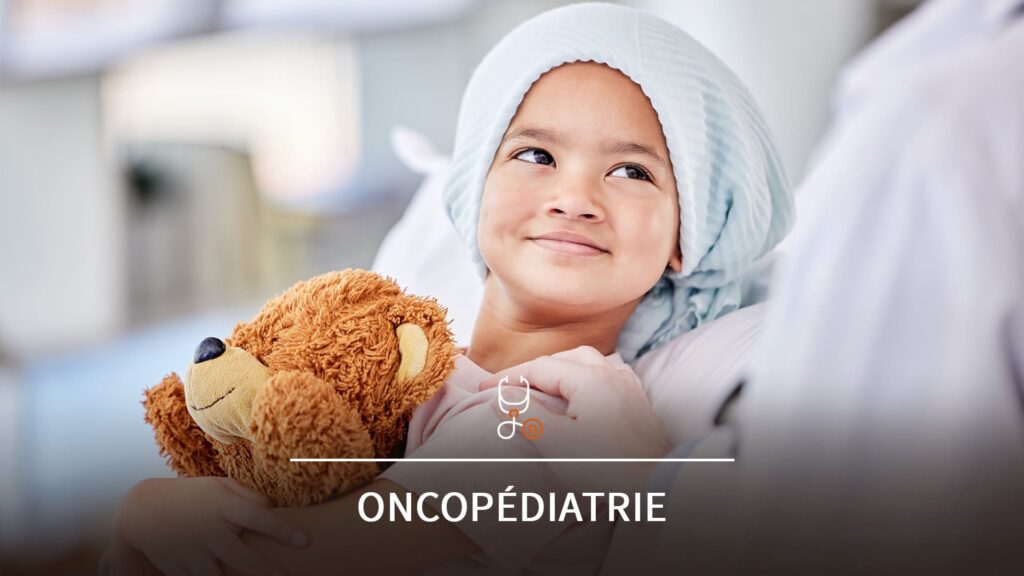 Enfant hospitalisé atteint de cancer, souriant et tenant un ours en peluche dans les bras.