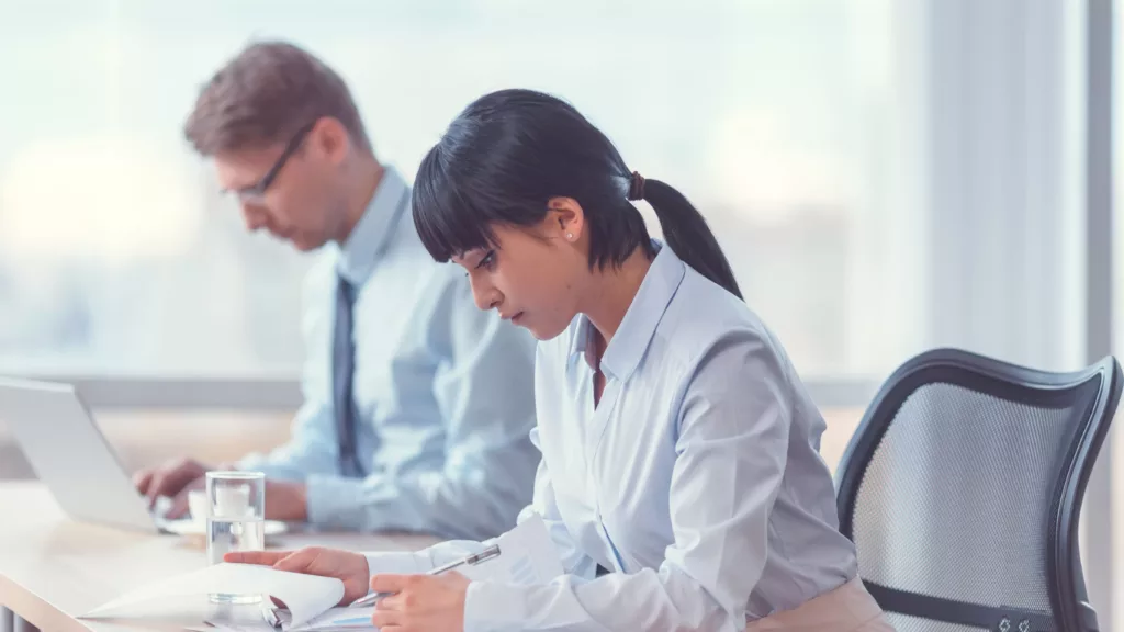 Deux professionnels concentrés en situation de travail, analysant des documents et des données, illustrant l’évaluation des pratiques professionnelles (EPP) dans le cadre du DPC.