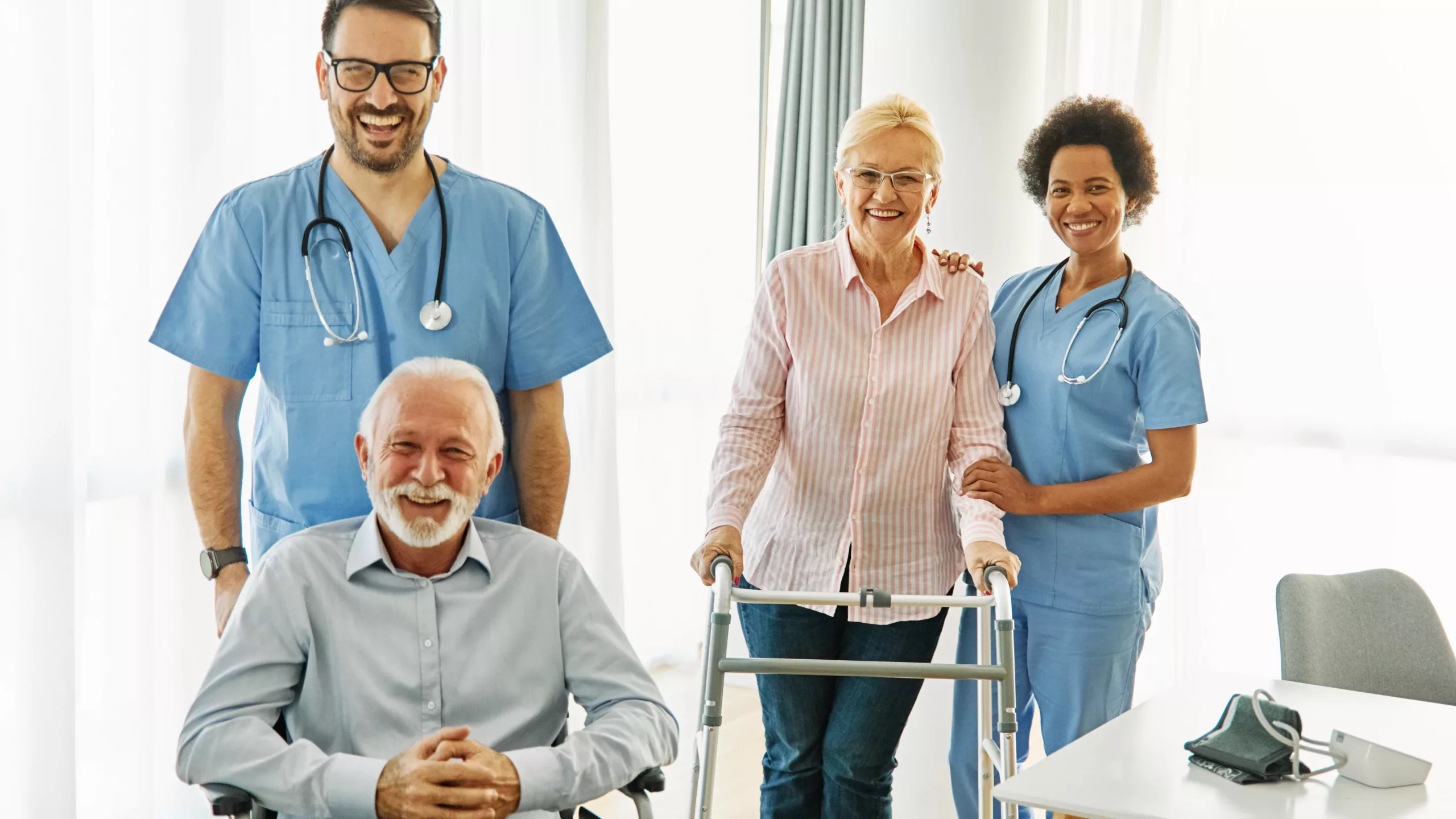Couple de séniors accompagné par deux professionnels de santé en cabinet médical, illustrant le suivi et le maintien de l’autonomie