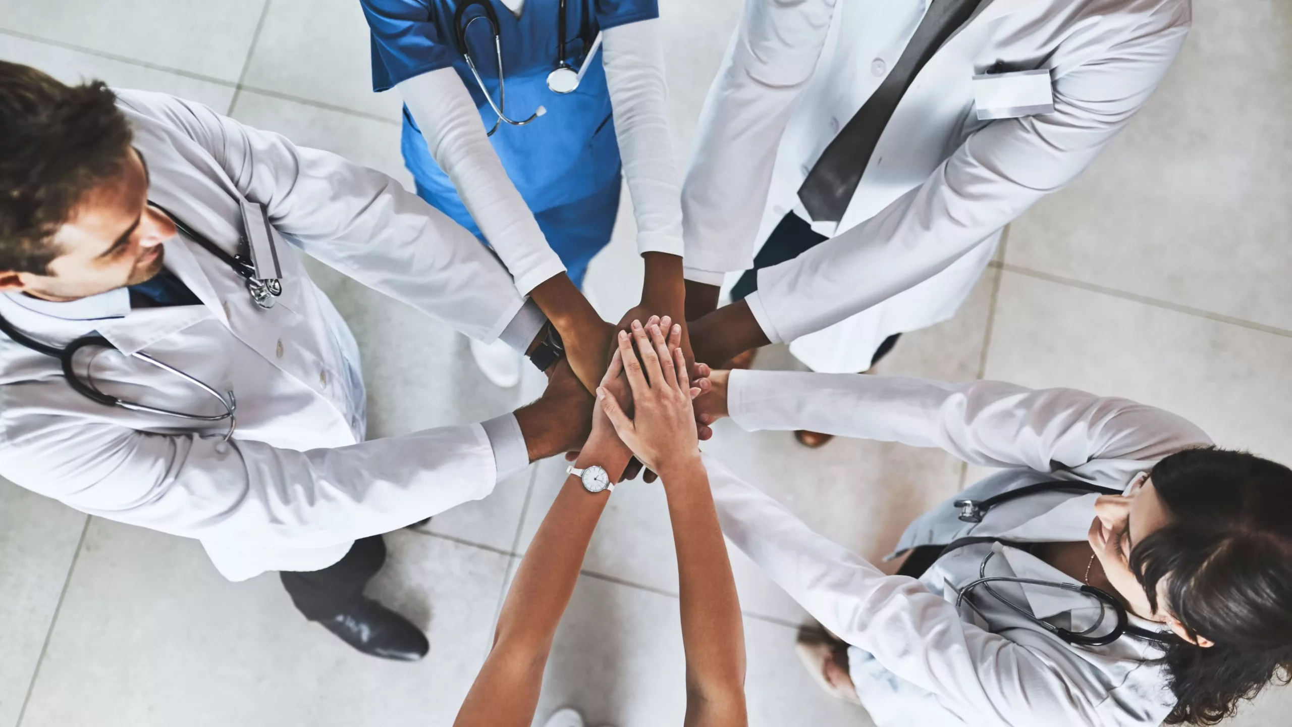Équipe de professionnels de santé unissant leurs mains pour symboliser la collaboration entre médecins et sages-femmes à propos des compétences sages-femmes